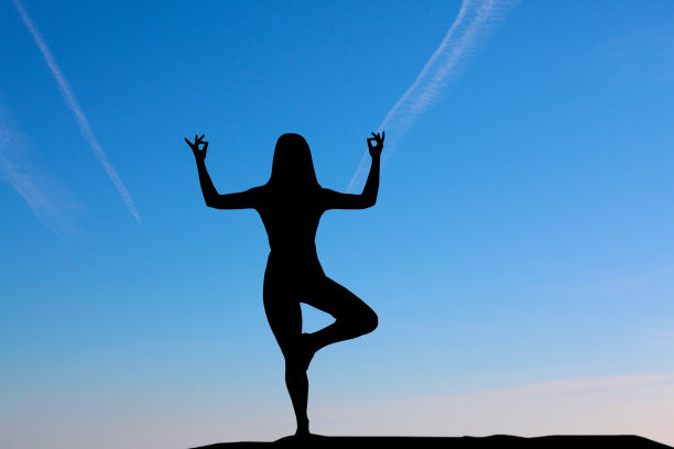 日落时在海边练习瑜伽的女人剪影。图片下载