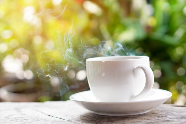 绿色背景的木桌上放着热咖啡杯素材图片