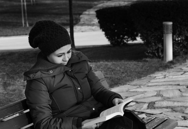 年轻女子在户外看一本书，黑白相间图片下载