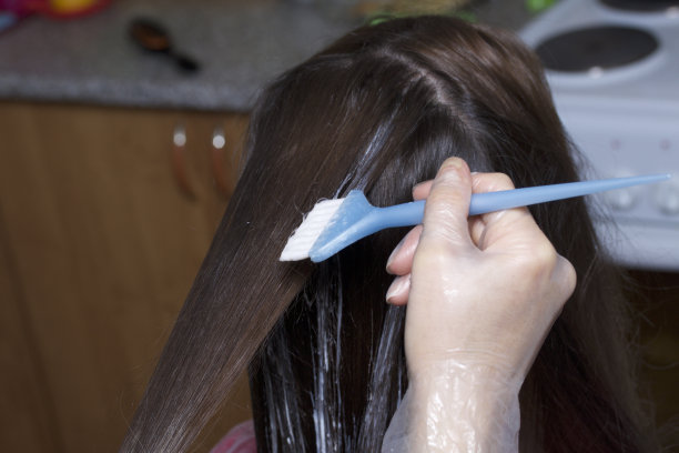 个体企业家在家提供服务。理发师给一个女人画头发。把颜料刷在线上。图片下载