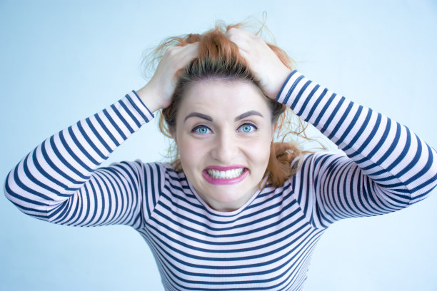 情绪化的露齿微笑的女孩抱着她的头图片下载