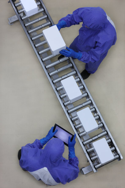 穿着蓝色制服的工人在包装线上处理箱子图片下载