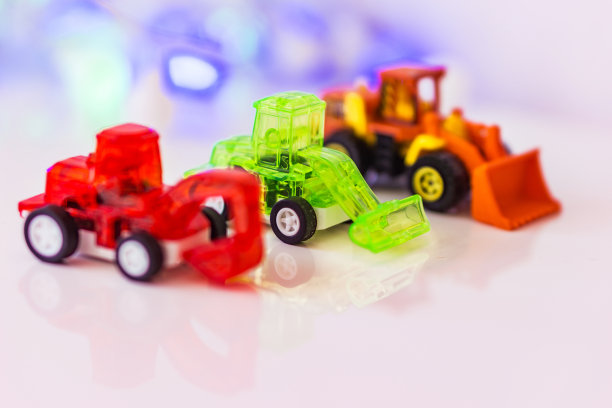 红色模糊的挖掘机、绿色装载机和模糊的装载机玩具，背景散景，运动技能概念图片下载