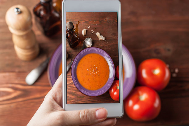 一男子用智能手机拍番茄酱汤图片下载