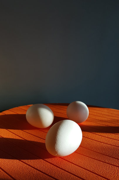 一组白色的鸡蛋在明亮的橙色表面图片下载