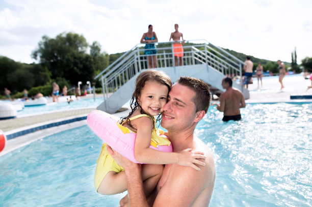 父亲和女儿在游泳池里。阳光明媚的夏天。图片下载