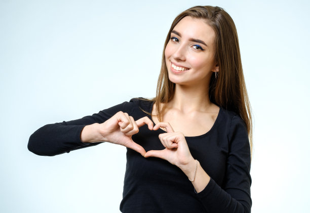 年轻漂亮的女孩做了一个心与她的手在白色的背景图片下载