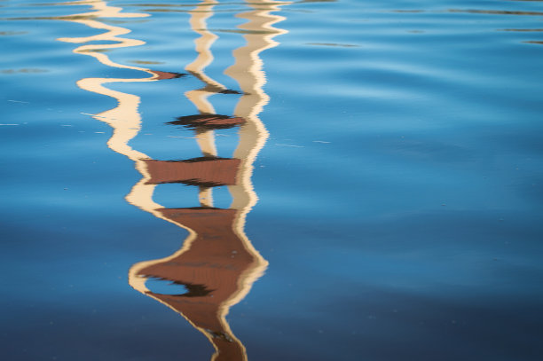 扭曲的电视塔在蓝色的水中的倒影。图片下载