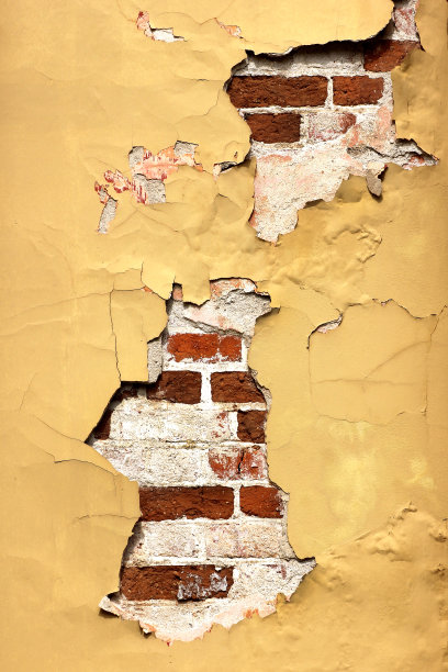 陈旧的砖砌成的黄色墙壁出现裂痕。图片下载