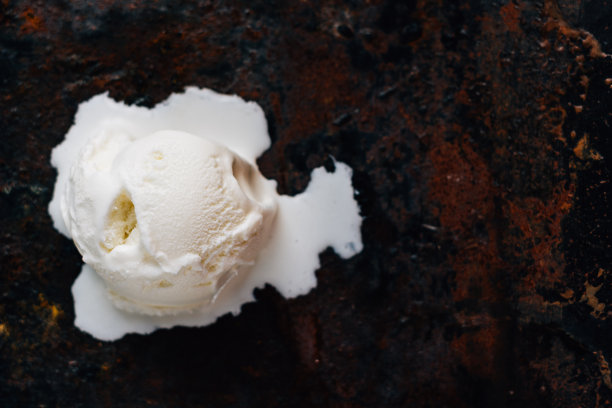 在黑色粗糙的表面上融化的冰淇淋球。图片下载