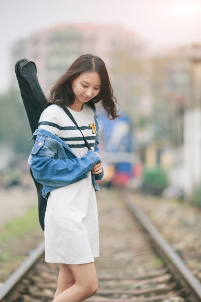 拿着吉他站在铁轨上的女孩。图片下载