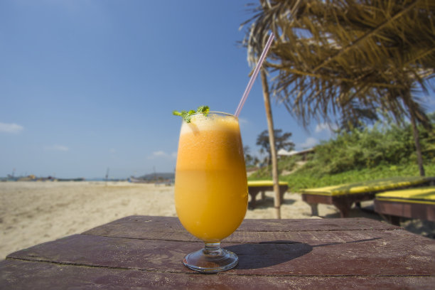 沙滩桌上放着一杯新鲜橙汁。图片下载