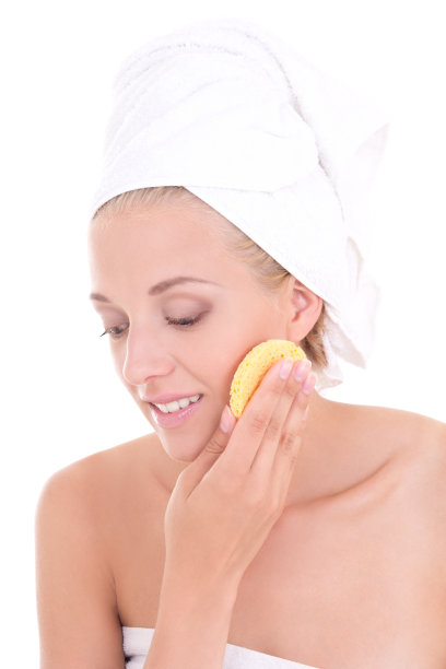 年轻迷人的女人用海绵洗她的脸在白色图片下载