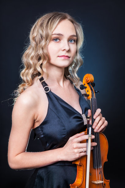 美丽的小提琴手在黑暗的背景上图片下载
