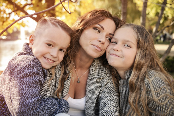 妈妈和孩子们在秋天公园的大树下。图片下载