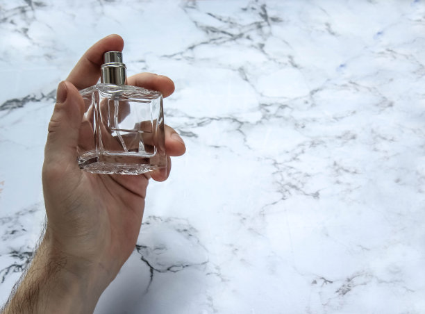 一个男人的手拿着一个装有香水的玻璃瓶图片下载