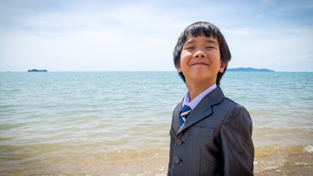 穿着西装的小男孩在海滩上图片下载