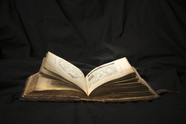 打开书，用灯光照亮文本。开卷阅读教育读者。在黑色背景上阅读古代圣经文本。俄罗斯《圣经》图片下载