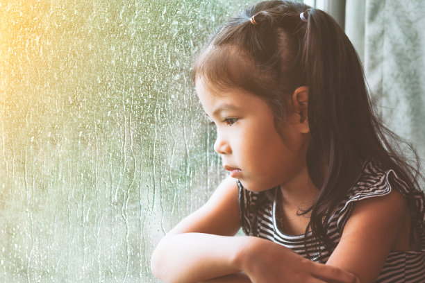 雨天里望着窗外的悲伤亚洲小女孩素材图片
