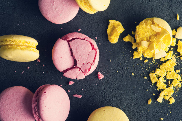 黑色混凝土背景上的粉色蛋白杏仁饼干的特写图片下载