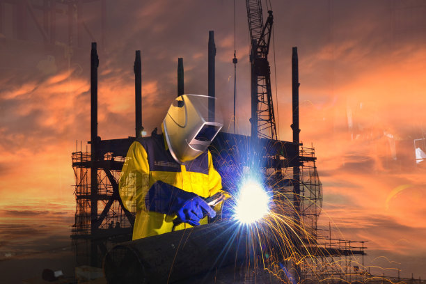 工业工人在工厂的双重暴露焊接和建筑背景。图片下载