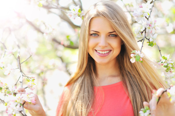 美丽的金发女郎站在盛开的树旁图片下载