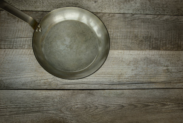 古老的金属平底锅在旧的木制背景。前视图。图片下载