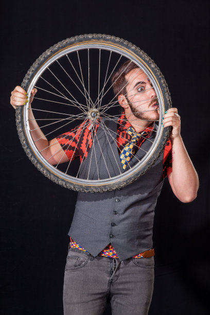 年轻人在自行车轮子上吹气图片下载