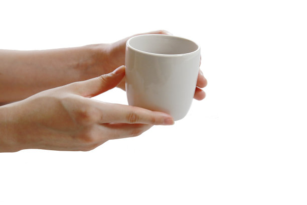 一只手拿着一只盛着果汁的白色杯子图片下载