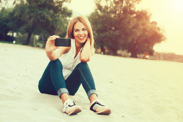 一个年轻女子在海滩上自拍图片下载