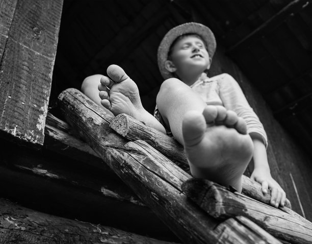 光着脚的男孩坐在谷仓的梯子上图片下载
