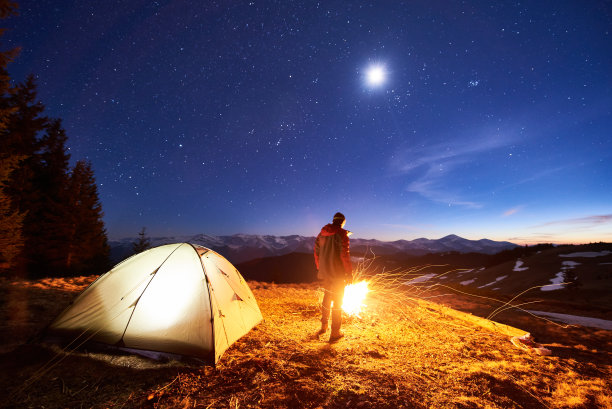 男游客在营地休息，在星空月色下享受山间夜景素材图片