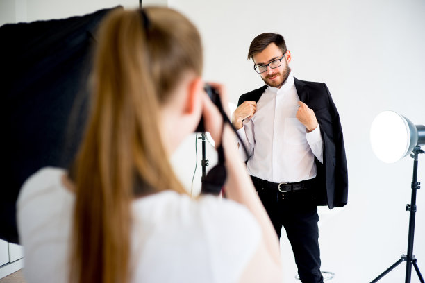 女摄影师在工作室拍摄一名男模特的照片图片下载