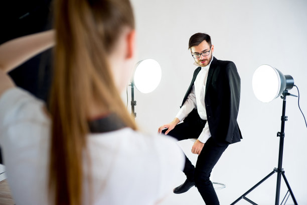 女摄影师在工作室拍摄一名男模特的照片图片下载