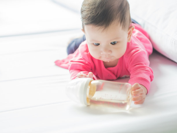 亚洲婴儿抱着奶瓶。图片下载