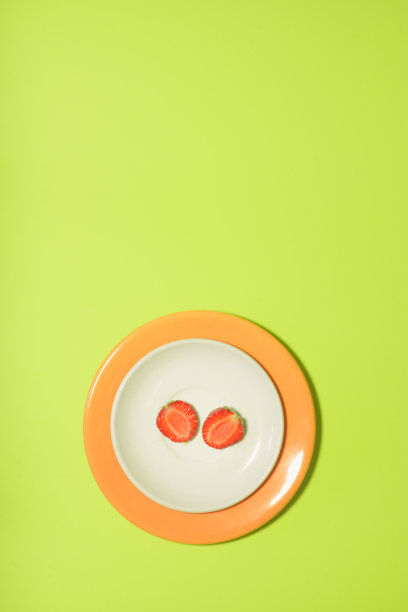 白色和橙色的盘子上放草莓片，背景是酸橙绿色。垂直设计的传单，横幅，封面或传单设计图片下载