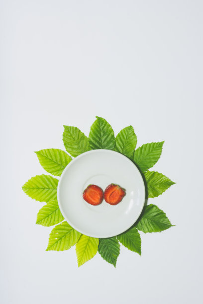 最小的草莓片背景。水果放在白色盘子里，周围是树叶。哑光色。垂直设计的传单，横幅，封面或传单图片下载