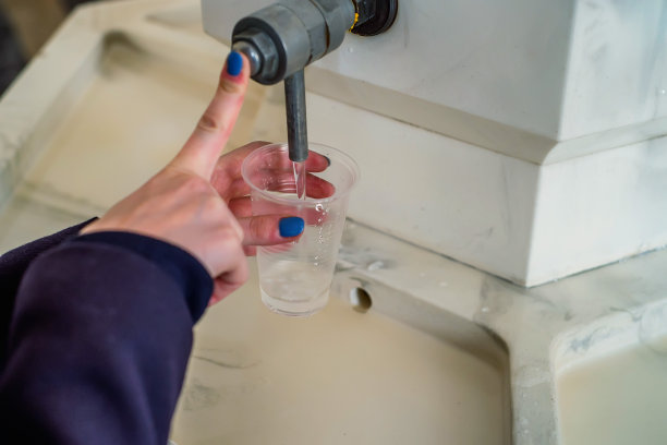 女人在泵房把矿泉水倒进玻璃杯里图片下载