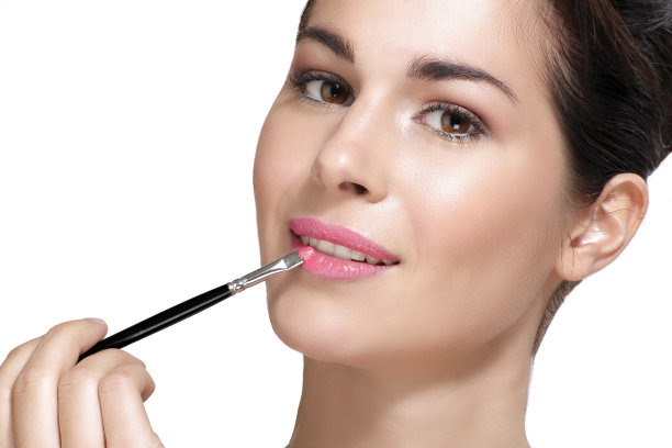 漂亮的年轻女子用刷子涂口红图片下载