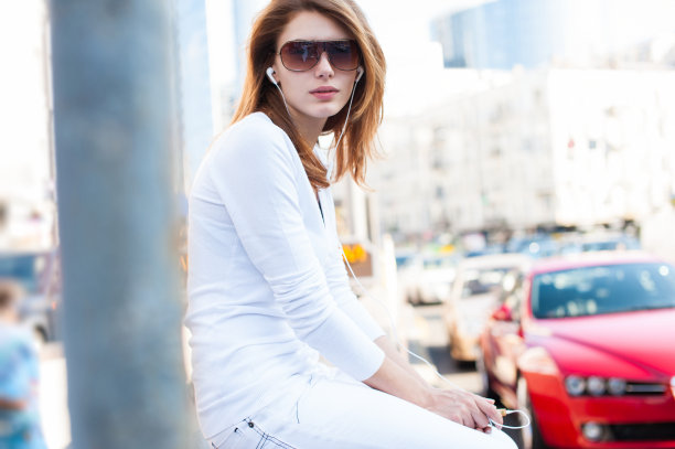 一个年轻女子坐在街道上，以城市为背景图片下载