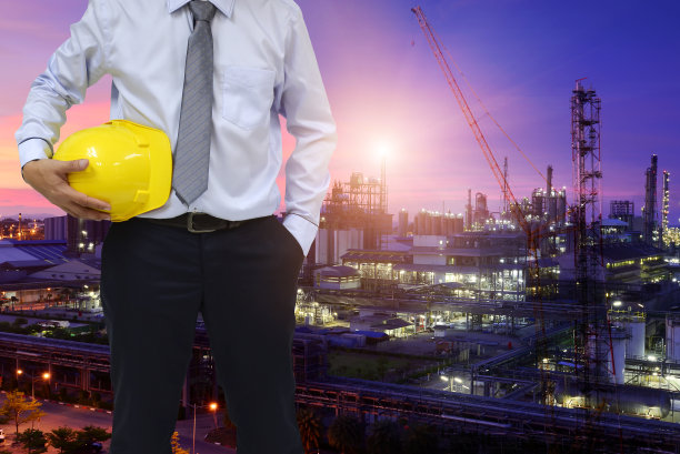 建筑工人概念。工程师持有头盔和炼油厂背景图片下载