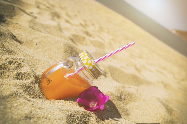 沙滩上的罐装橙汁。夏天的概念。图片下载