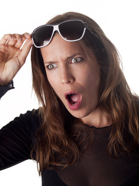 美丽的黑发女子举起她的太阳镜震惊了图片下载