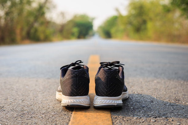 新的黑色跑鞋在柏油路在早上的时间图片下载