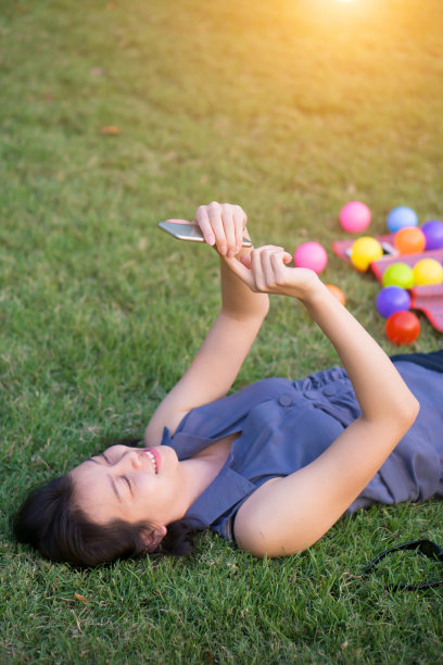 年轻女子在绿草地上触摸智能手机图片下载