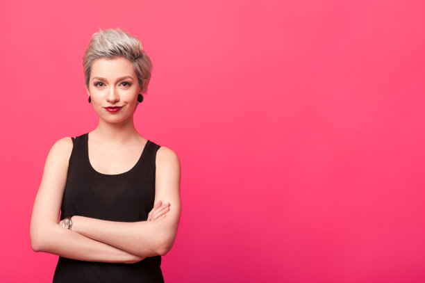 自信的女人双臂交叉，孤立地站在粉红色的背景上图片下载