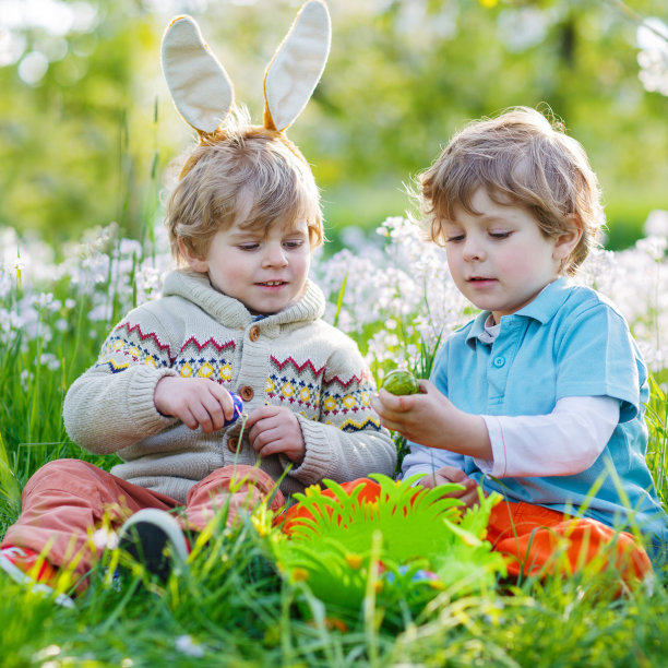 两个小孩子戴着复活节兔子耳朵，吃着巧克力图片下载