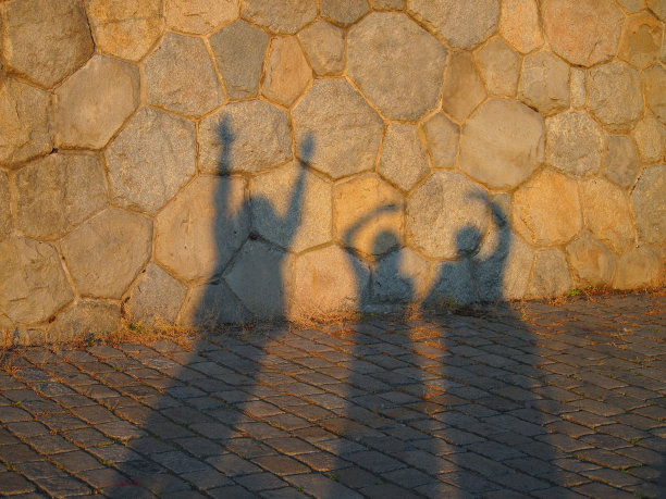 旧石墙上有三个朋友的影子。布拉格伏尔塔瓦河边的夏日快乐。图片下载