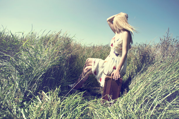 一个女人在荒野里坐在她的行李箱上图片下载