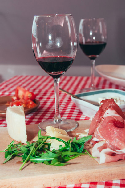 桌上放着芝士、意大利火腿和芝麻菜，还有两杯红酒图片下载
